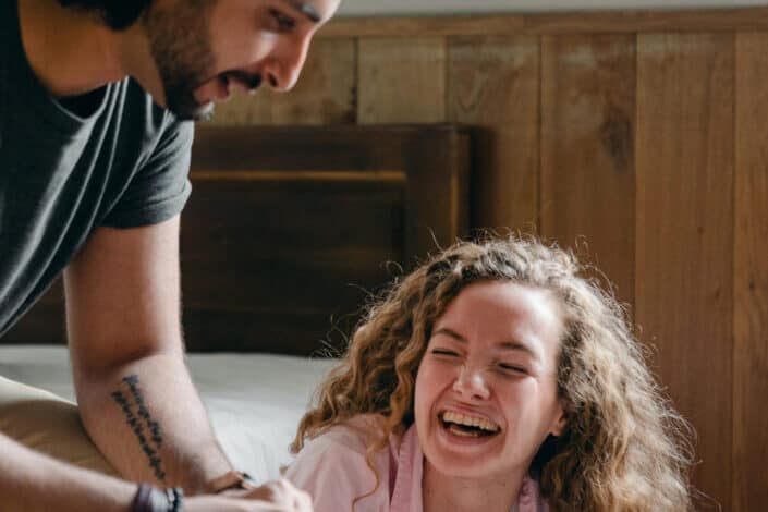 Cheerful couple unboxing stuff in bedroom