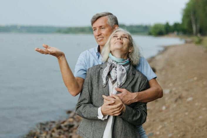 Man Hugging a Woman Near Lakeshore