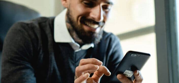 Smiling Man Using a Smartphone