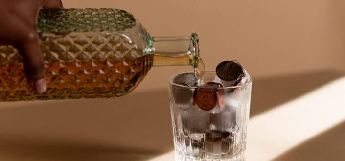 person pouring liquor in a clear glass