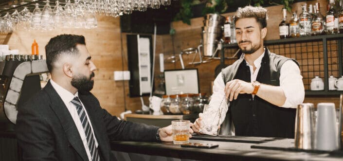 Bartender serving a drink to a man in suit