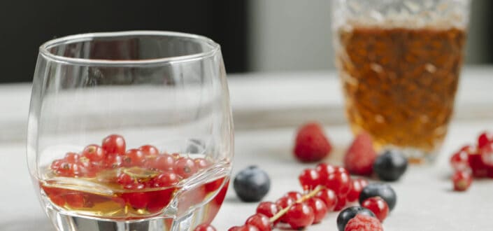 Glass of whiskey on table with berries