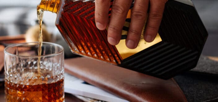 Person pouring liquor in drinking glass