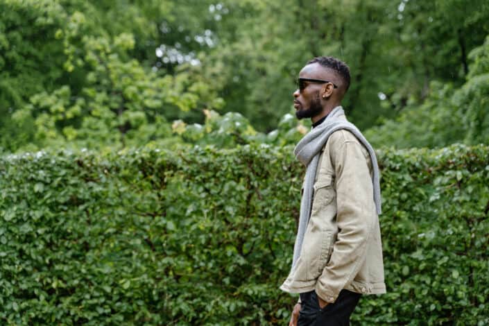 Young man walking in a garden full of green bushes