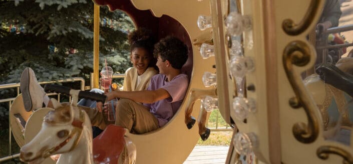 Teenagers sitting in carousel seat smiling and talking to each other