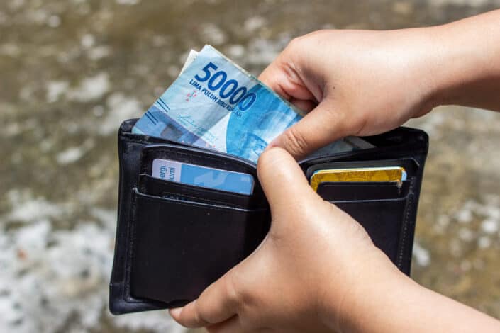 A hand putting paper money inside wallet