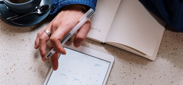 Person holding pen and using a tablet