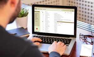 A man typing an email on a laptop.